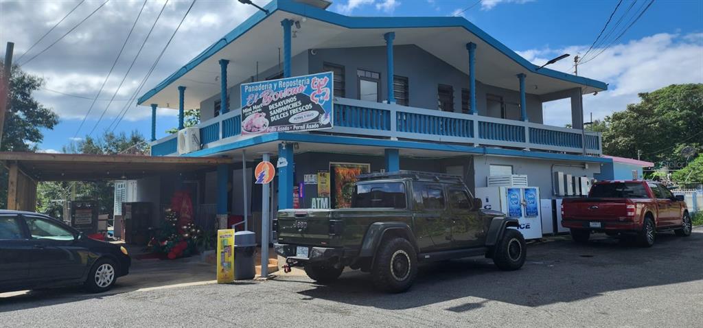 A two-story building with a blue-trimmed balcony, a parking area, and a bakery sign — Carr. 414, Km 3.6 BO. RÍO GRANDE, RINCON, PR