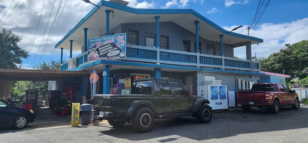 A two-story commercial building with a blue balcony and parked vehicles in front — Carr. 414, Km 3.6 BO. RÍO GRANDE, RINCON, PR