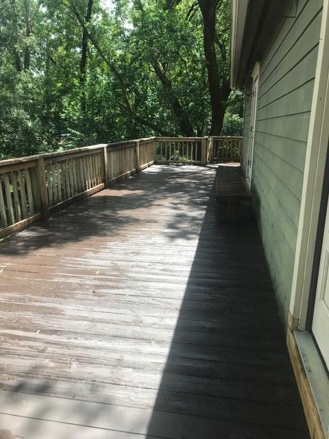 A wooden deck with a railing overlooks trees next to a house with green siding — 2513 Colleen, Tallahassee FL 32303, TALLAHASSEE, FL