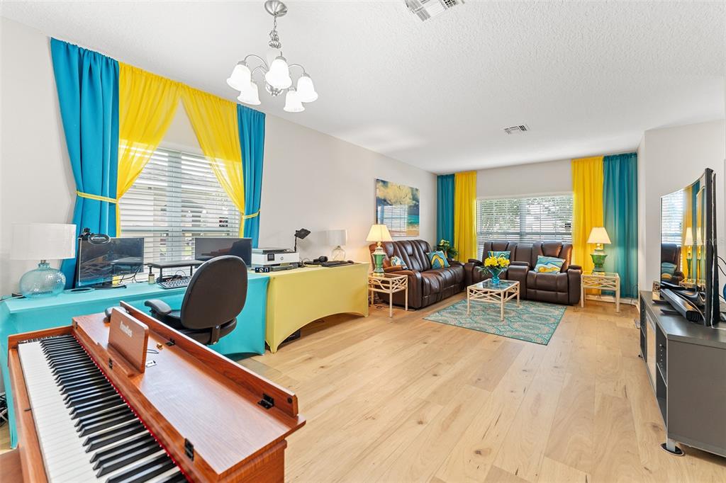 A living room features a piano, a desk area, brown leather sofas, and bright curtains — 3605 CAPE COURT, ST CLOUD, FL