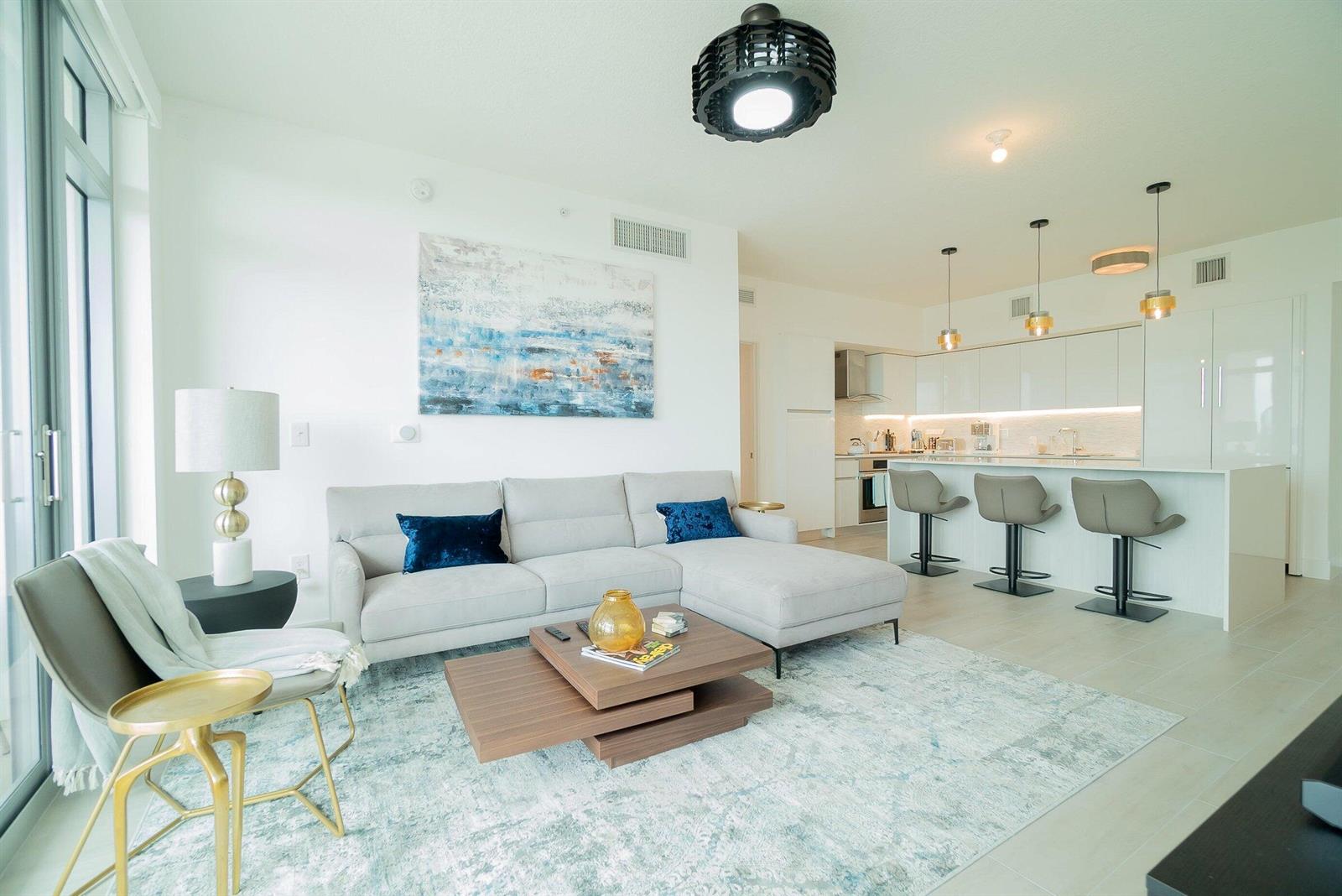 A modern open-concept living room and kitchen featuring a grey sectional, coffee table, and island — 111 SE 1st Avenue # 514, Delray Beach FL 33444, DELRAY BEACH, FL