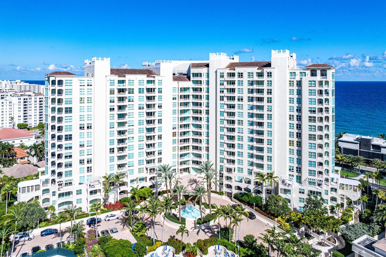An aerial view of a large white multi-story residential building with palm trees and landscaping — 3700 S Ocean Boulevard # 202, Highland Beach FL 33487, HIGHLAND BEACH, FL