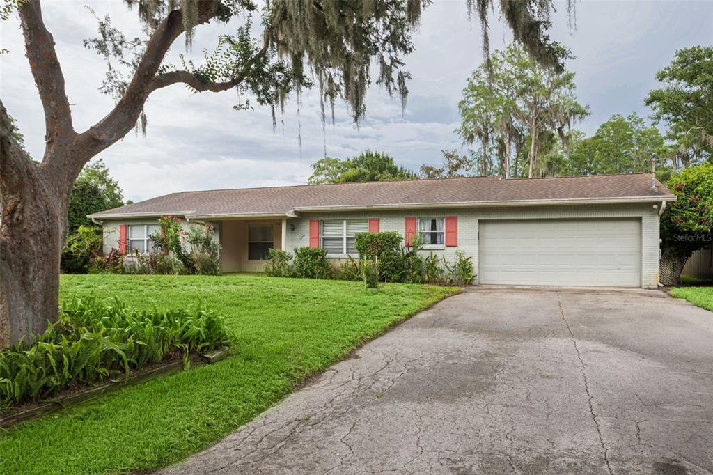 A single-story brick house with a two-car garage, red shutters, and a large front lawn — 2801 WILSON CIRCLE, LUTZ, FL