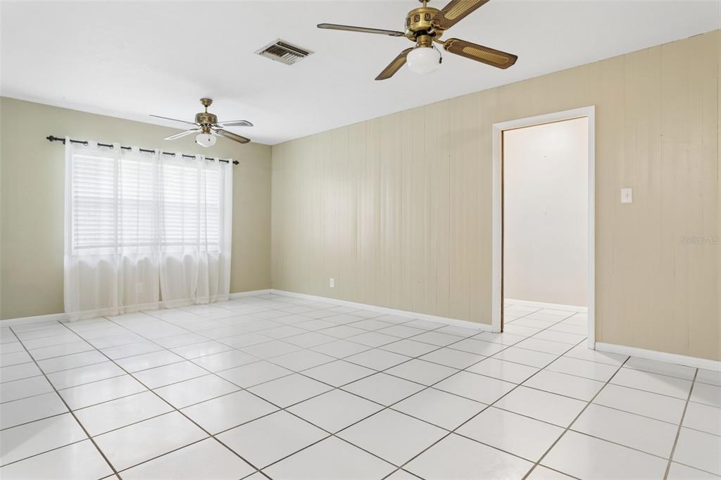 A room with white tiled floors, beige paneled walls, two ceiling fans, and a window — 2801 WILSON CIRCLE, LUTZ, FL