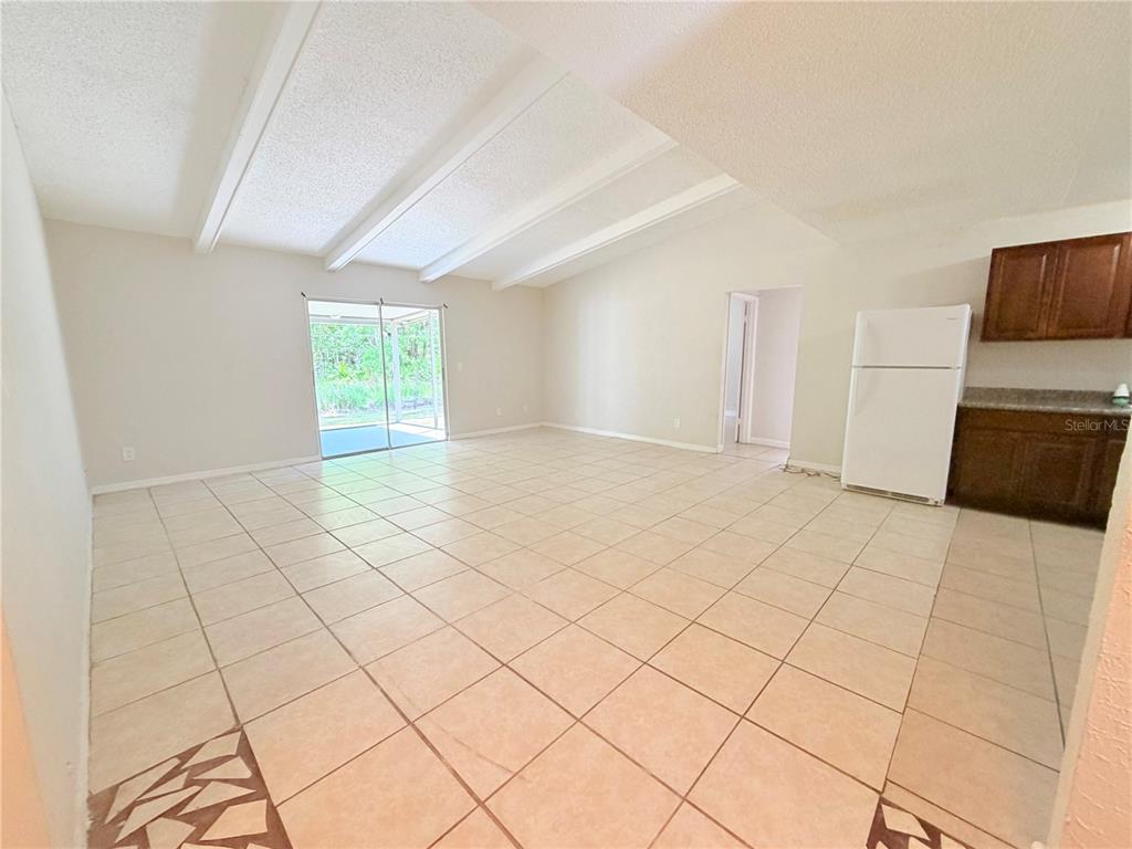 An open-concept living area features vaulted ceilings, tile flooring, and a sliding glass door — 336 MONTGOMERY COURT, KISSIMMEE, FL