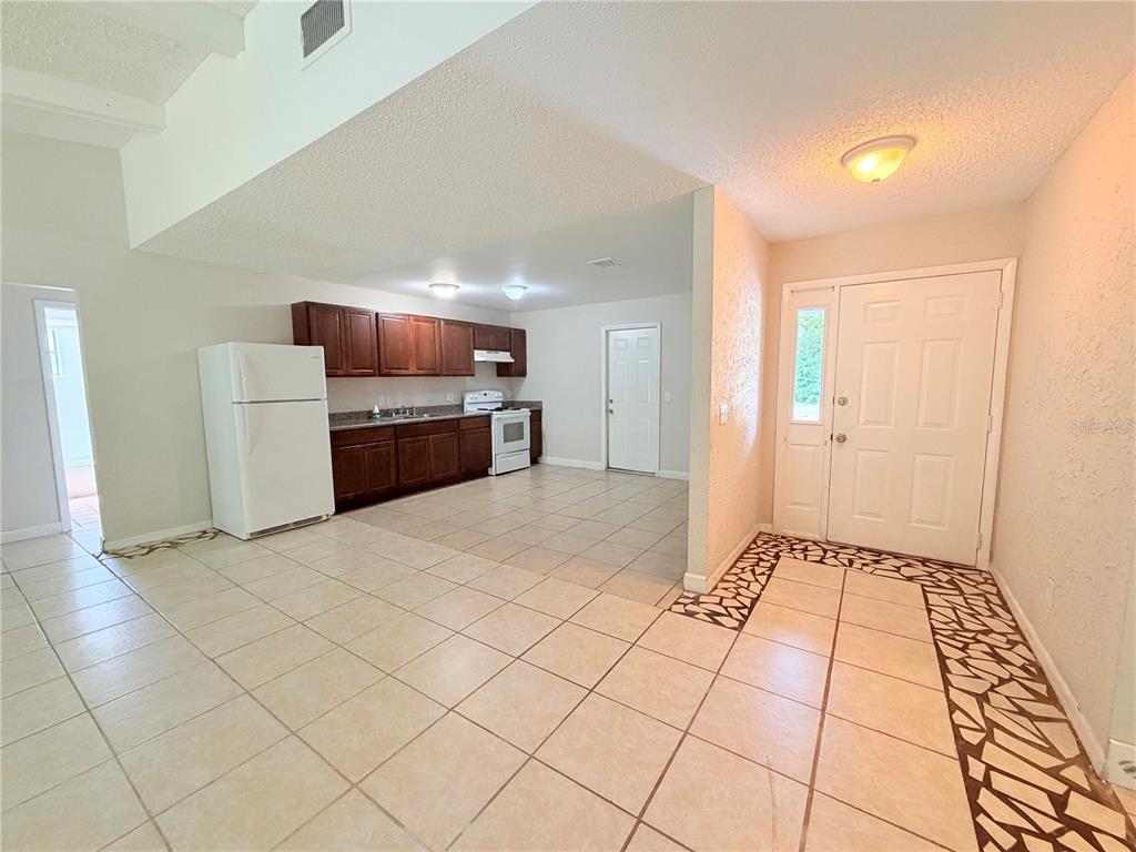 An open-concept kitchen with dark wood cabinets and tile flooring connects to the entryway — 336 MONTGOMERY COURT, KISSIMMEE, FL