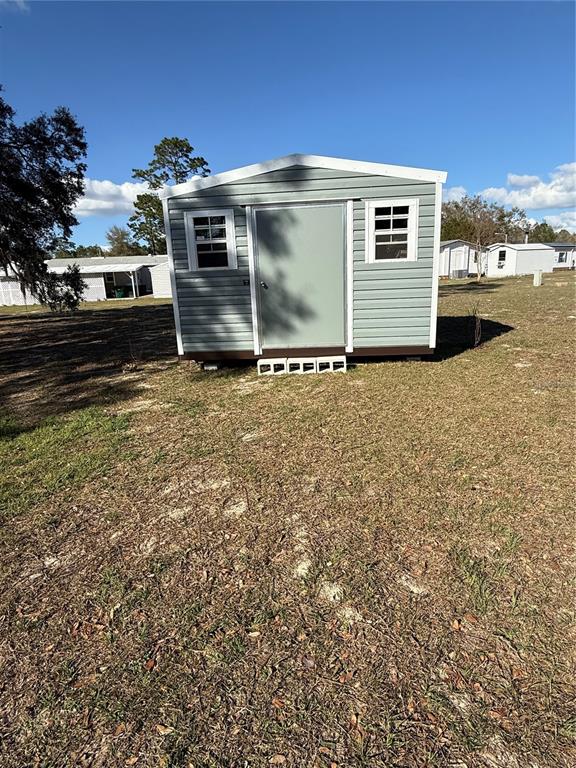 The exterior of a house features a screened-in porch, a white door, and septic tank covers — 8325 N FAIRGROVE TERRACE, DUNNELLON, FL