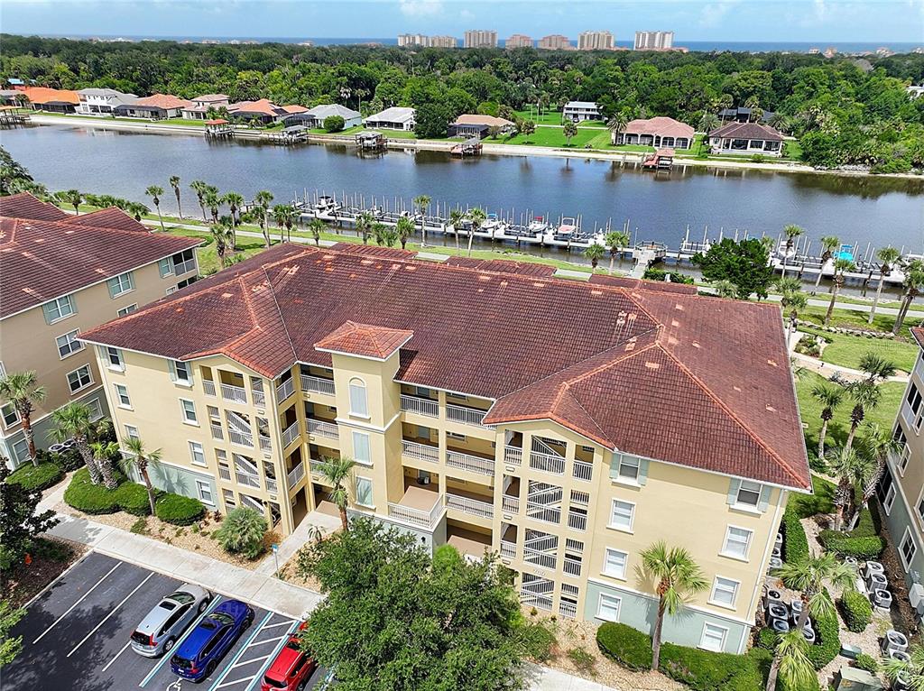 An aerial view shows a multi-story apartment building with a tiled roof near a canal — 700 CANOPY WALK LANE UNIT 713, PALM COAST, FL