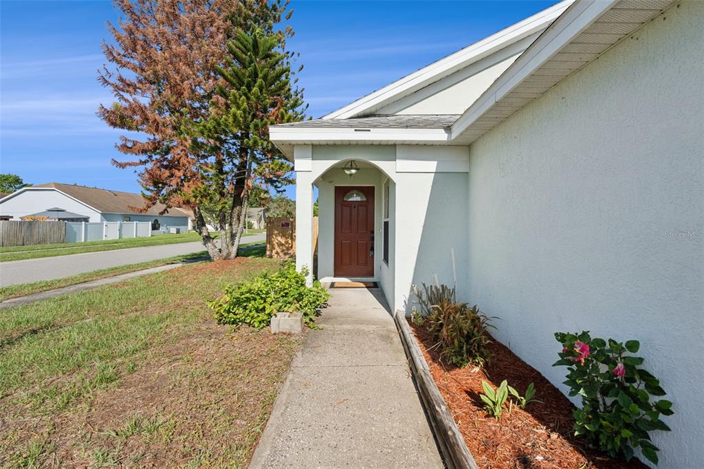 A concrete walkway leads to the front entrance of a house with a brown door — 948 RIVECON AVENUE, ORLANDO, FL