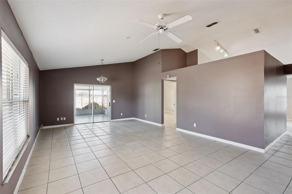An empty living room with gray walls, tile flooring, a ceiling fan, and sliding glass doors — 948 RIVECON AVENUE, ORLANDO, FL