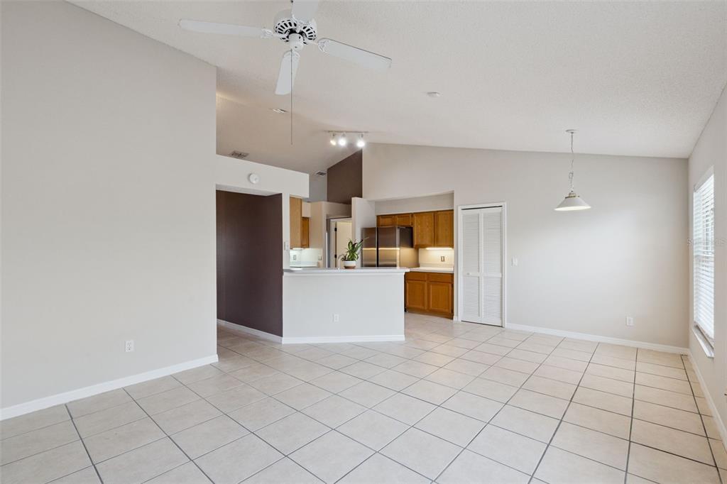 An open-concept living area features light tile flooring, a vaulted ceiling, and a kitchen — 948 RIVECON AVENUE, ORLANDO, FL