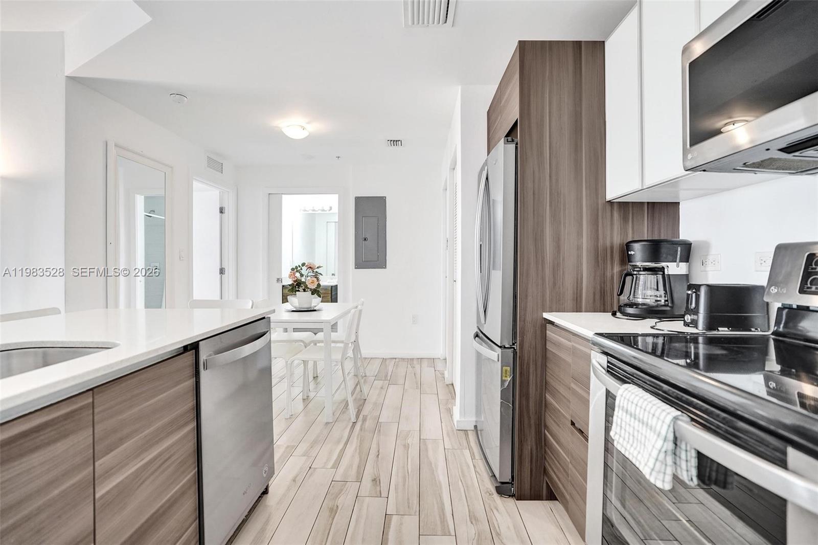A modern kitchen features wood-grain cabinetry, stainless steel appliances, and light-colored tile flooring — 481 NE 29th St # 702, Miami FL 33137, MIAMI, FL