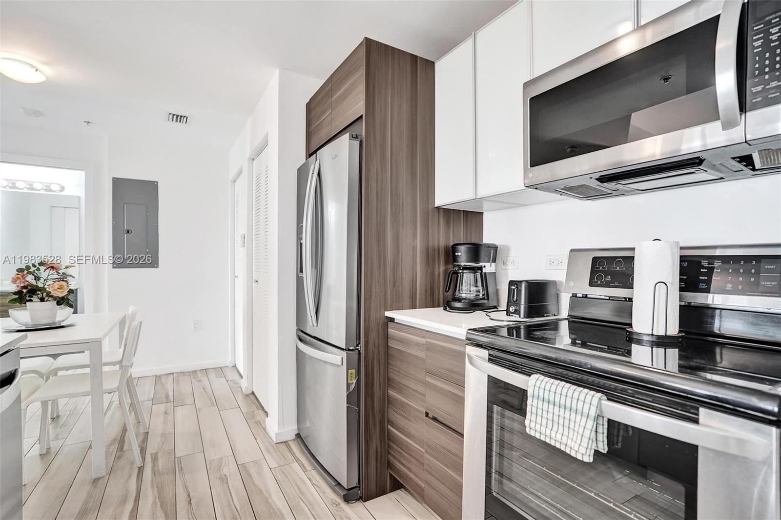 A modern kitchen features stainless steel appliances, wood-grain cabinetry, white upper cabinets, and light flooring — 481 NE 29th St # 702, Miami FL 33137, MIAMI, FL