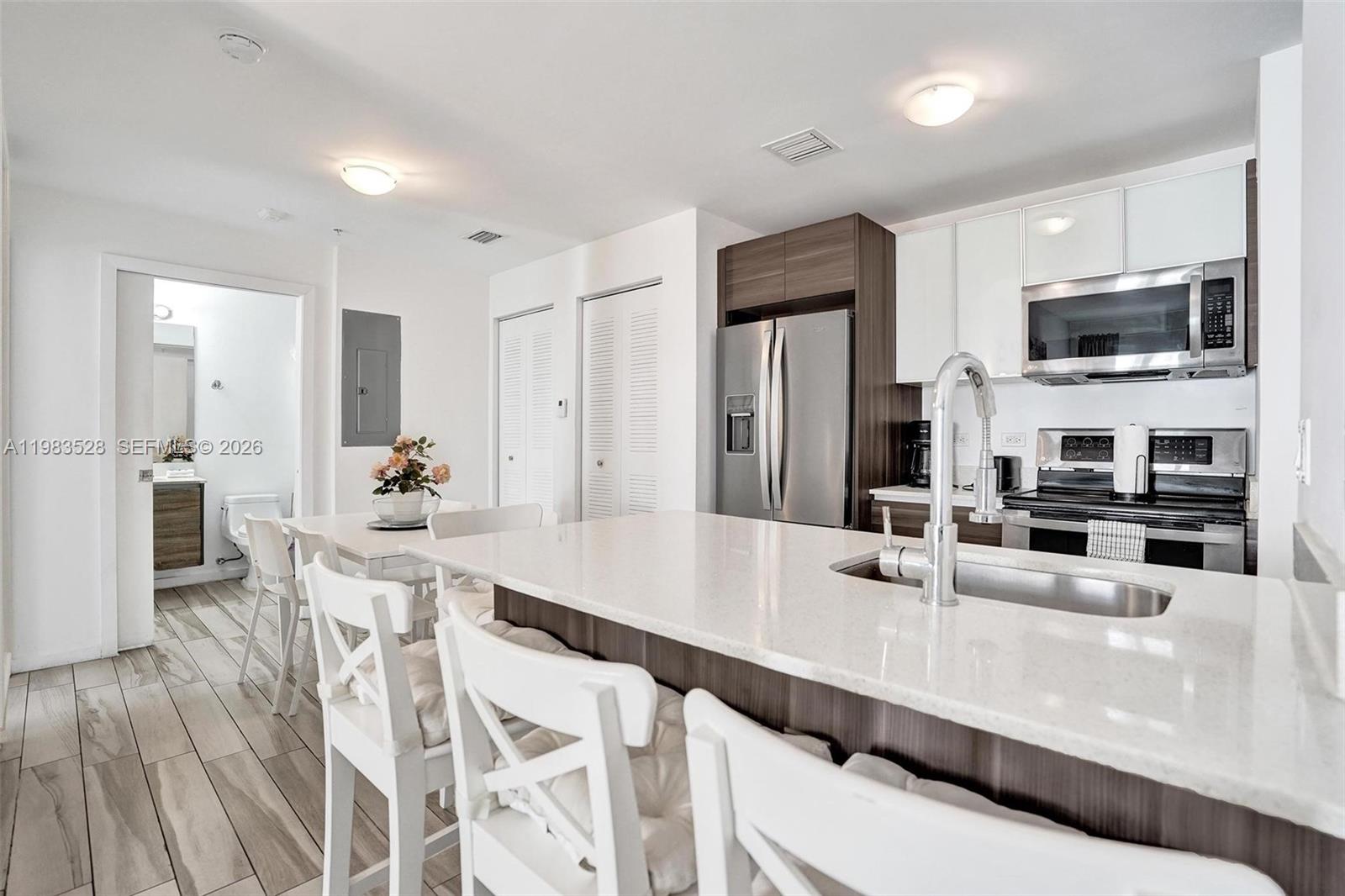 A modern kitchen features white cabinets, stainless steel appliances, and a large quartz island — 481 NE 29th St # 702, Miami FL 33137, MIAMI, FL