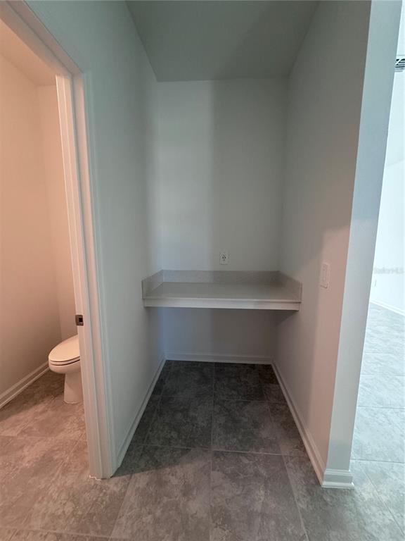A small alcove with a built-in desk sits next to a bathroom with tiled flooring — 1952 ROCK MAPLE BEND, KISSIMMEE, FL