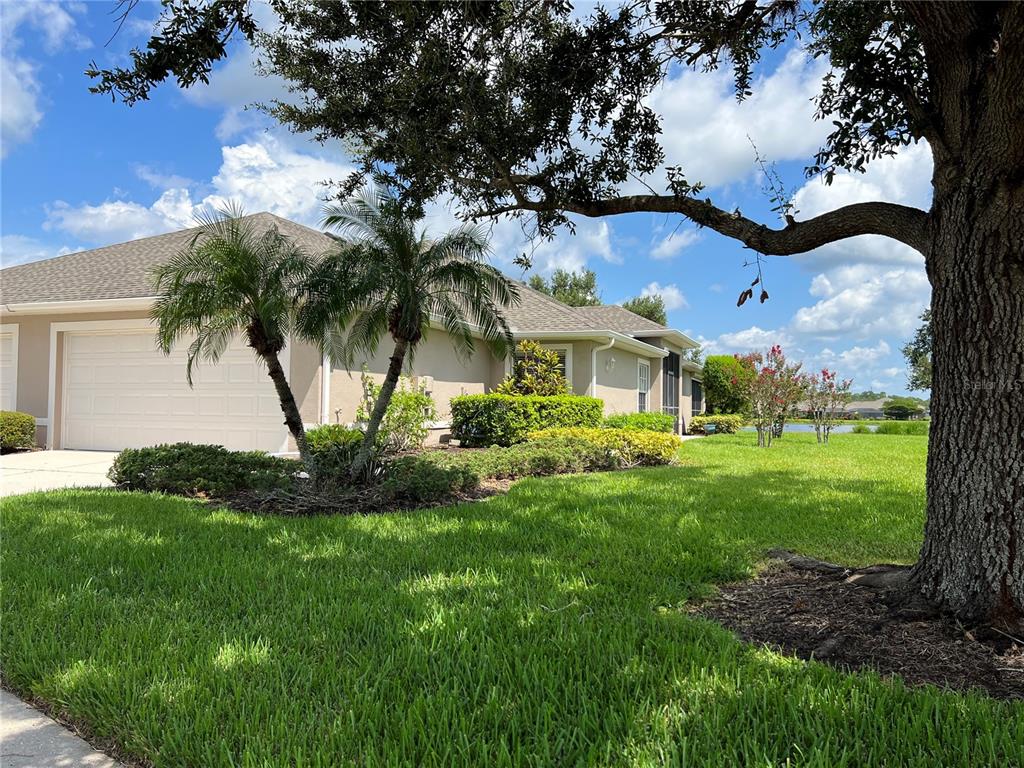 A single-story house with a two-car garage, palm trees, and a large oak tree — 3653 LAKEWOOD BOULEVARD, NORTH PORT, FL