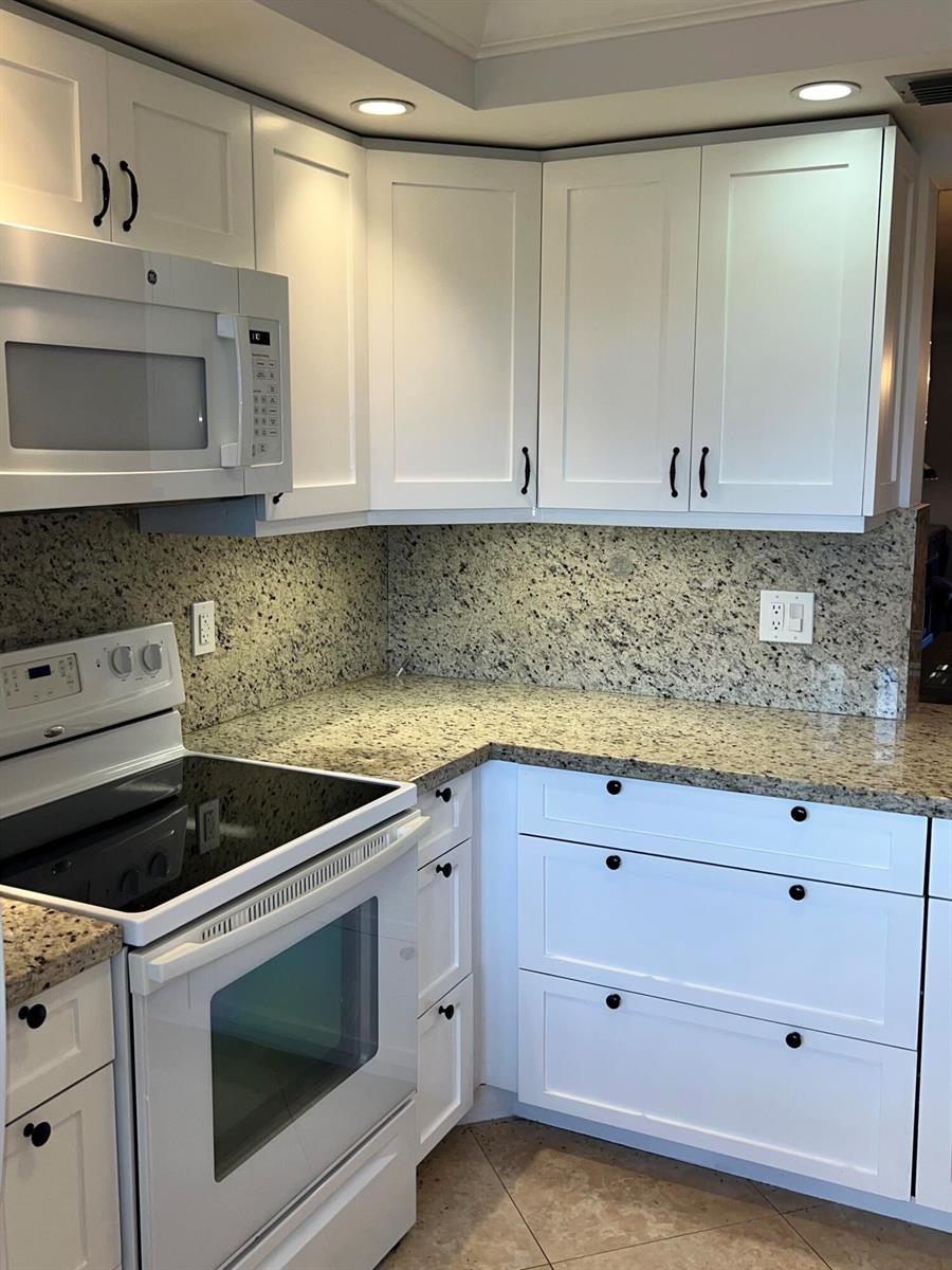 A kitchen features white cabinets, granite countertops, a white stove, and a built-in microwave — 2202 Lucaya Bend # C4, Coconut Creek FL 33066, COCONUT CREEK, FL