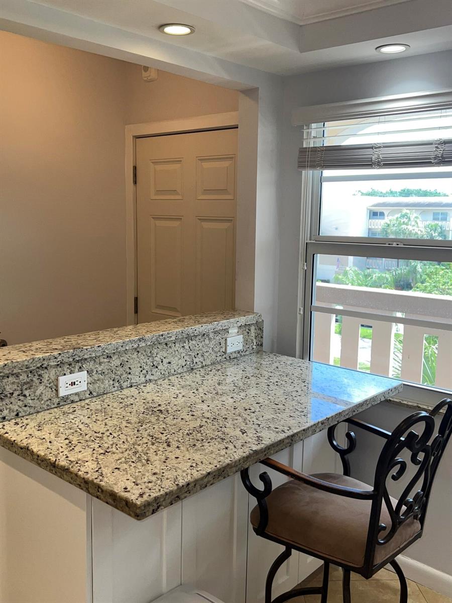 A granite breakfast bar with two electrical outlets sits next to a window with blinds — 2202 Lucaya Bend # C4, Coconut Creek FL 33066, COCONUT CREEK, FL