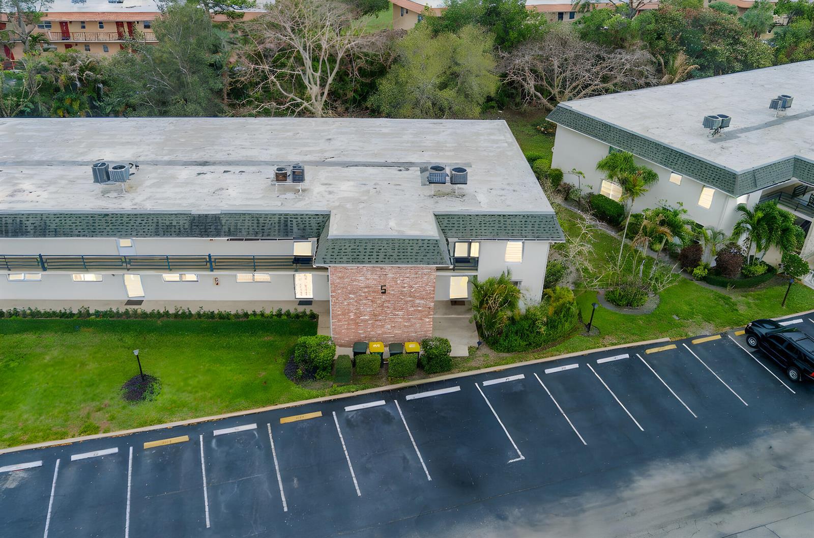 An aerial view shows a two-story apartment building with a brick facade and parking lot — 1900 S Kanner Highway # 5107, Stuart FL 34994, STUART, FL