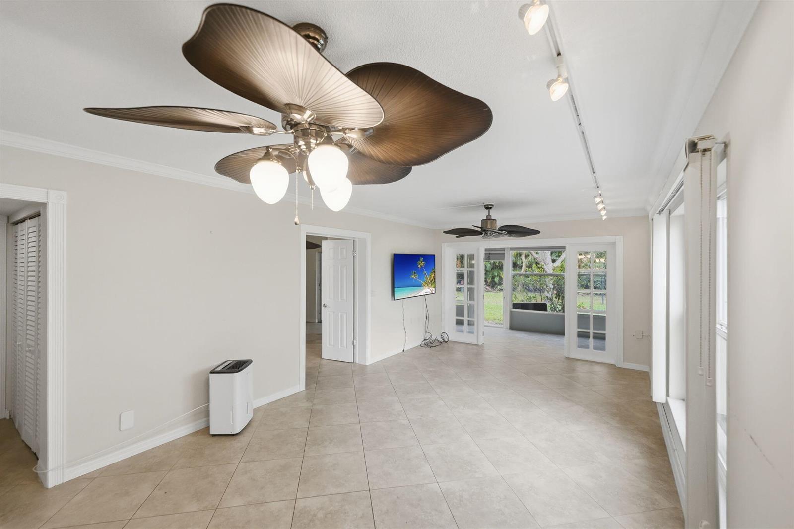 A living room with tile flooring, two ceiling fans, and a wall-mounted television — 1900 S Kanner Highway # 5107, Stuart FL 34994, STUART, FL