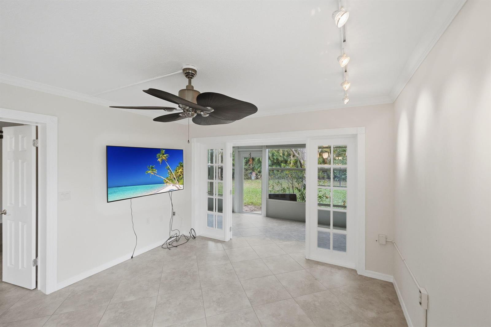 A room with tile flooring, a ceiling fan, a wall-mounted television, and French doors leading outside — 1900 S Kanner Highway # 5107, Stuart FL 34994, STUART, FL