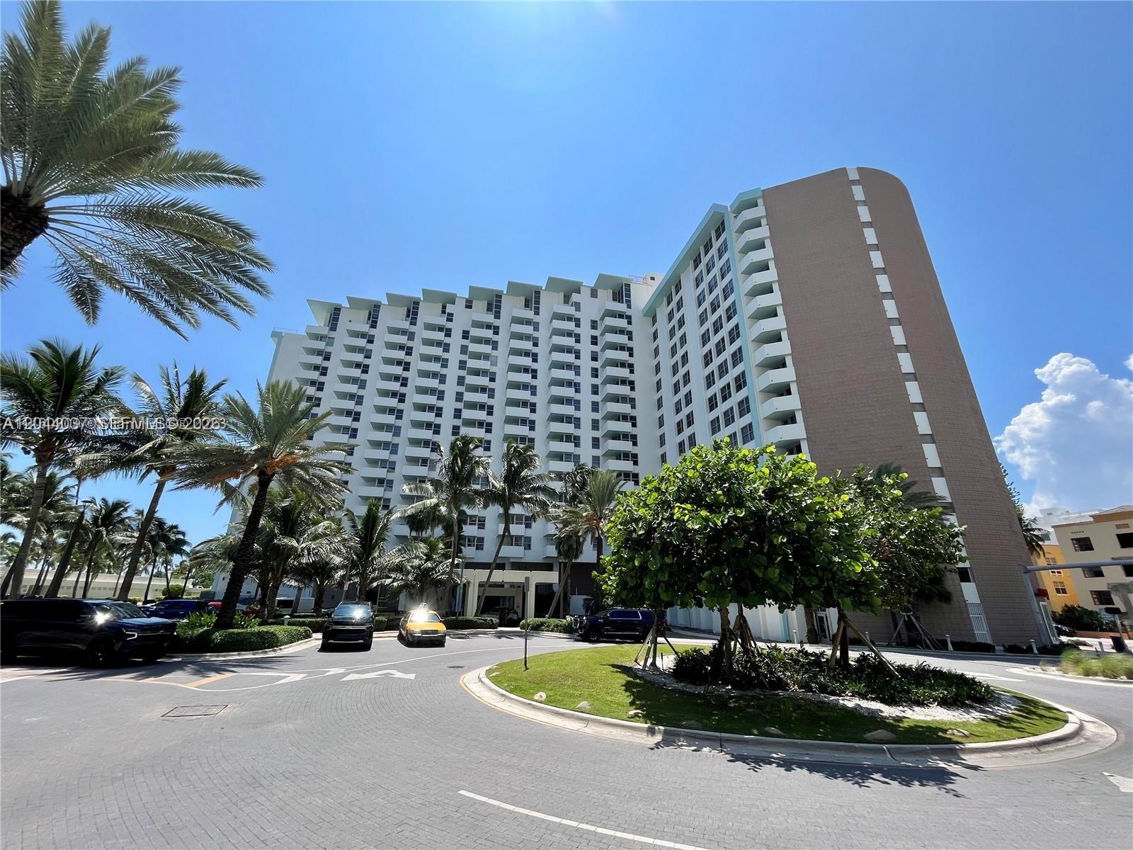 A multi-story residential building features balconies and palm trees in a circular driveway area — 2899 Collins Ave # 1726, Miami Beach FL 33140, MIAMI BEACH, FL