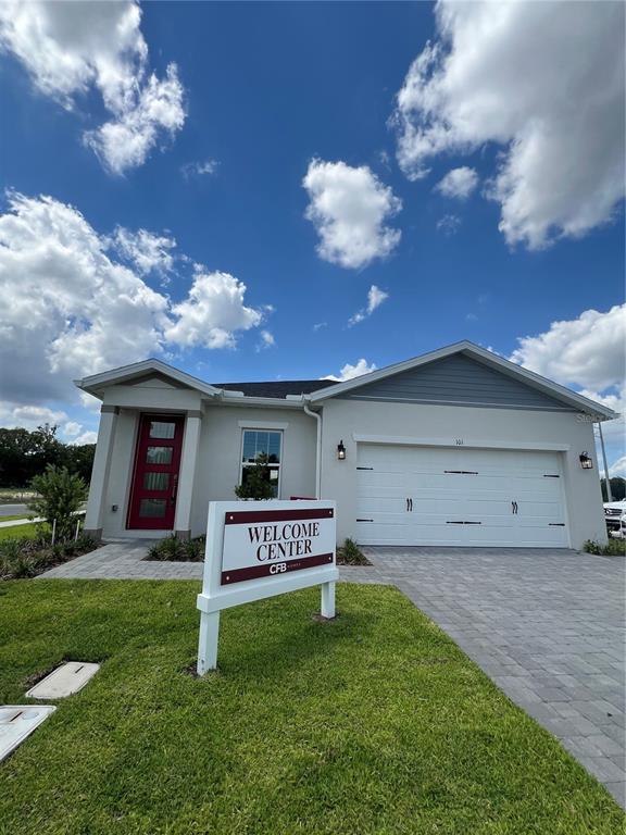 A single-story house with a white garage, red front door, and a welcome center sign — 101 ELENA LAVIN CIRCLE, ORLANDO, FL