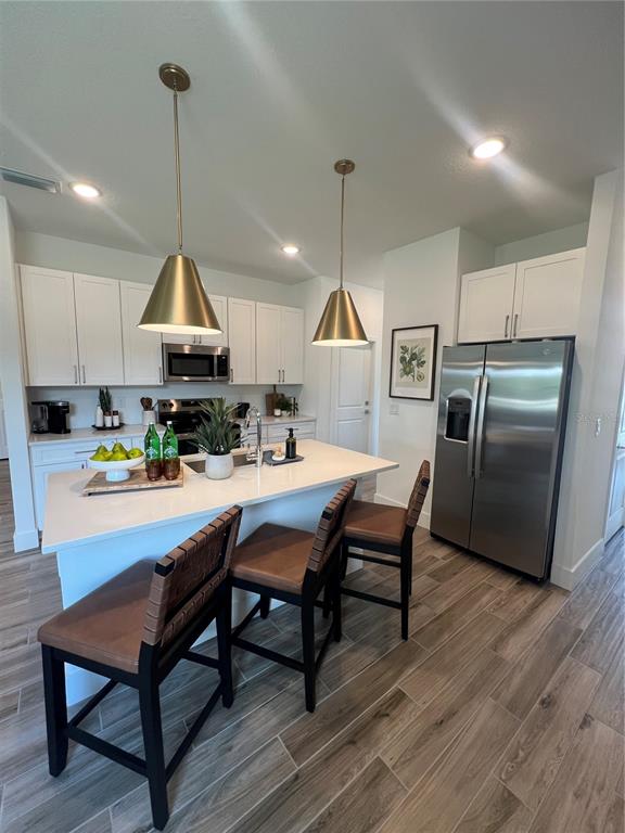 A modern kitchen features white cabinets, a central island with bar stools, and stainless appliances — 101 ELENA LAVIN CIRCLE, ORLANDO, FL