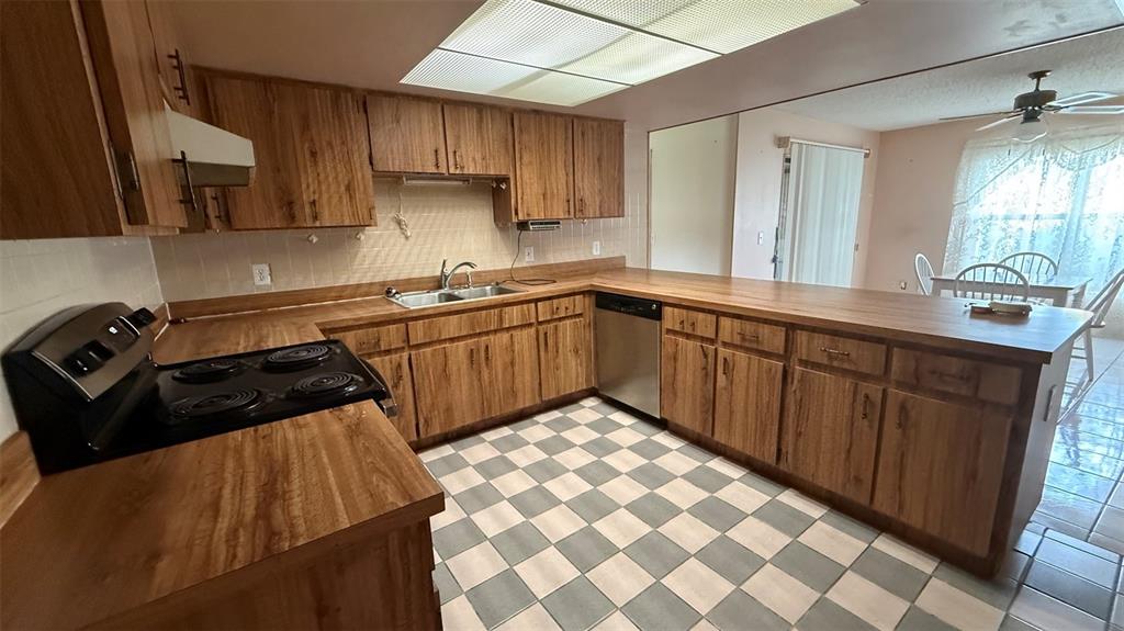 A kitchen features wood cabinets, laminate countertops, a checkered floor, and a stainless steel dishwasher — 15165 SW 39TH CIRCLE, OCALA, FL