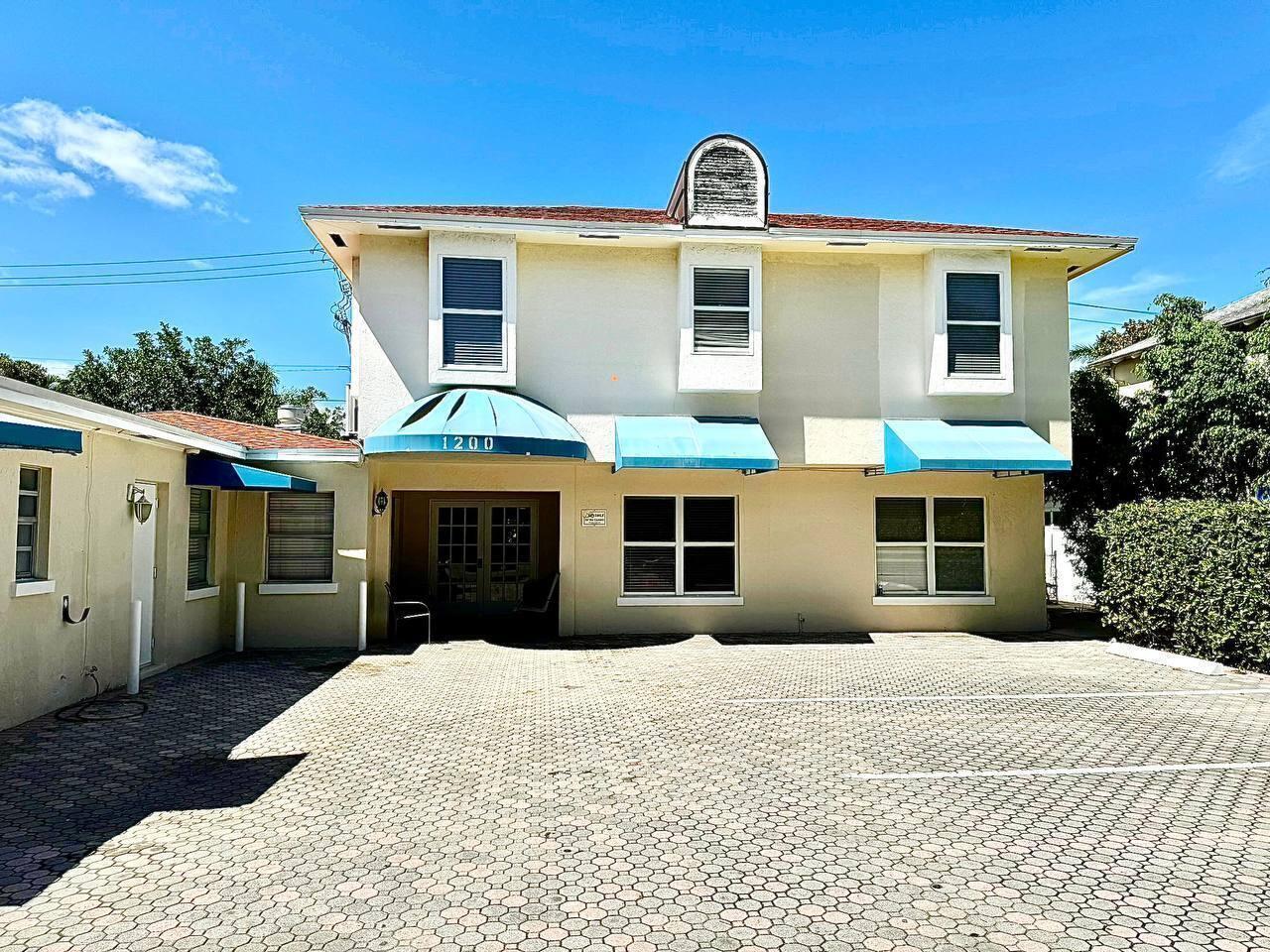A two-story building with a beige stucco exterior, blue awnings, and a paved parking lot — 1200 Surf Road, Singer Island FL 33404, SINGER ISLAND, FL