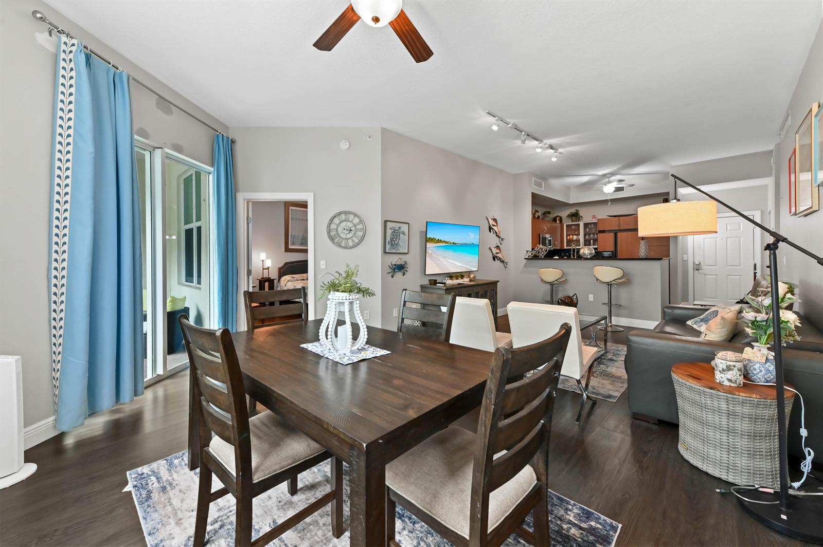 An open-concept living and dining area features dark wood floors, a kitchen bar, and furniture — 804 E Windward Way # 120, Lantana FL 33462, LANTANA, FL