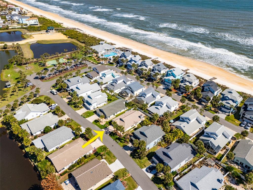 An aerial view shows a coastal neighborhood with houses situated near a sandy beach — 9 SEA VISTA DRIVE, PALM COAST, FL