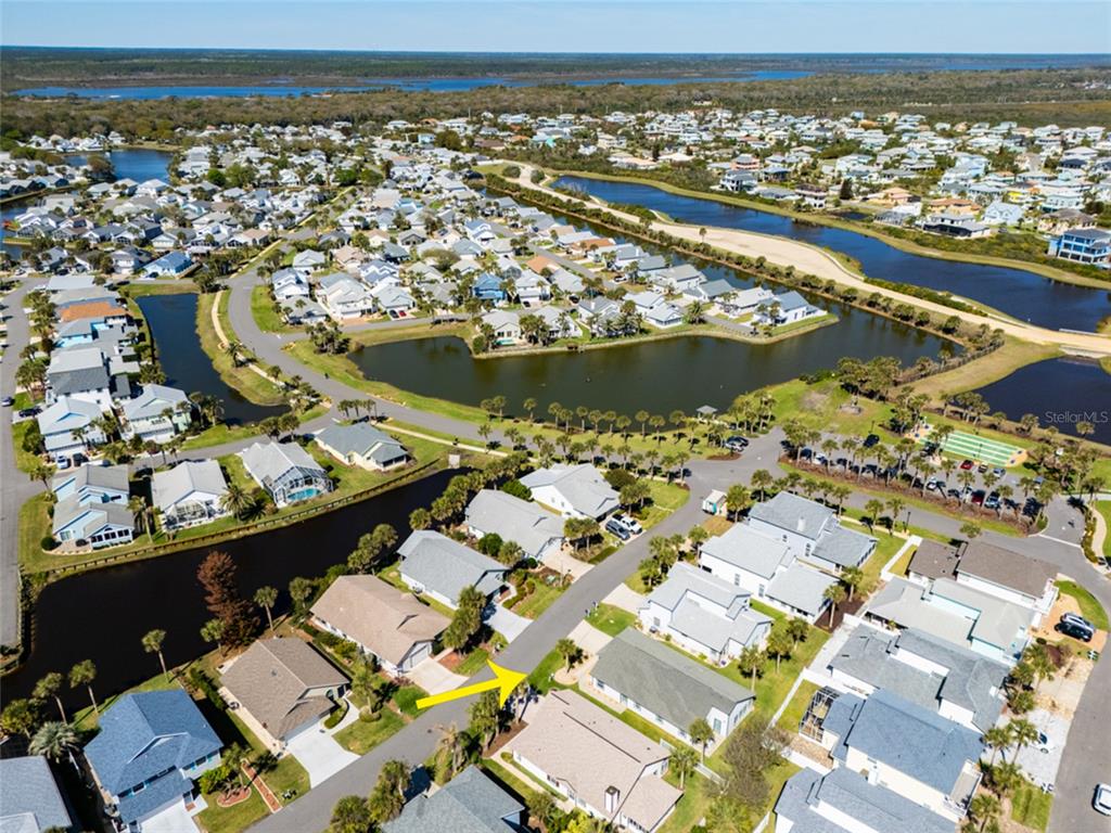 An aerial view shows a suburban neighborhood with houses, a canal, and a pond — 9 SEA VISTA DRIVE, PALM COAST, FL