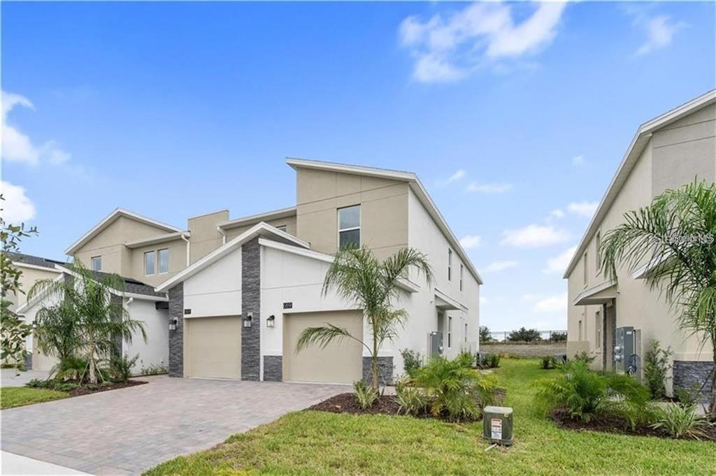 A two-story townhome with a two-car garage, stone accents, and a paved driveway — 659 OCEAN COURSE AVENUE UNIT 659, DAVENPORT, FL