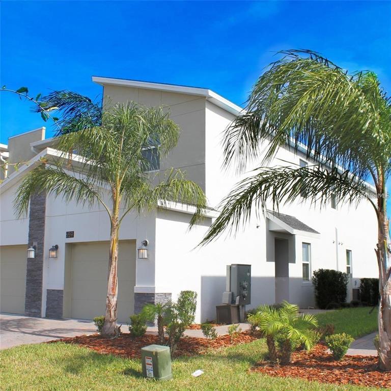 A two-story townhouse exterior features white stucco walls, a garage, and palm trees — 659 OCEAN COURSE AVENUE UNIT 659, DAVENPORT, FL