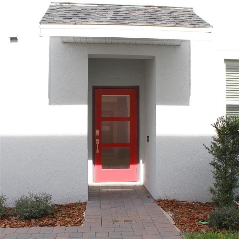 A red front door with three glass panels sits under a small roof overhang — 659 OCEAN COURSE AVENUE UNIT 659, DAVENPORT, FL