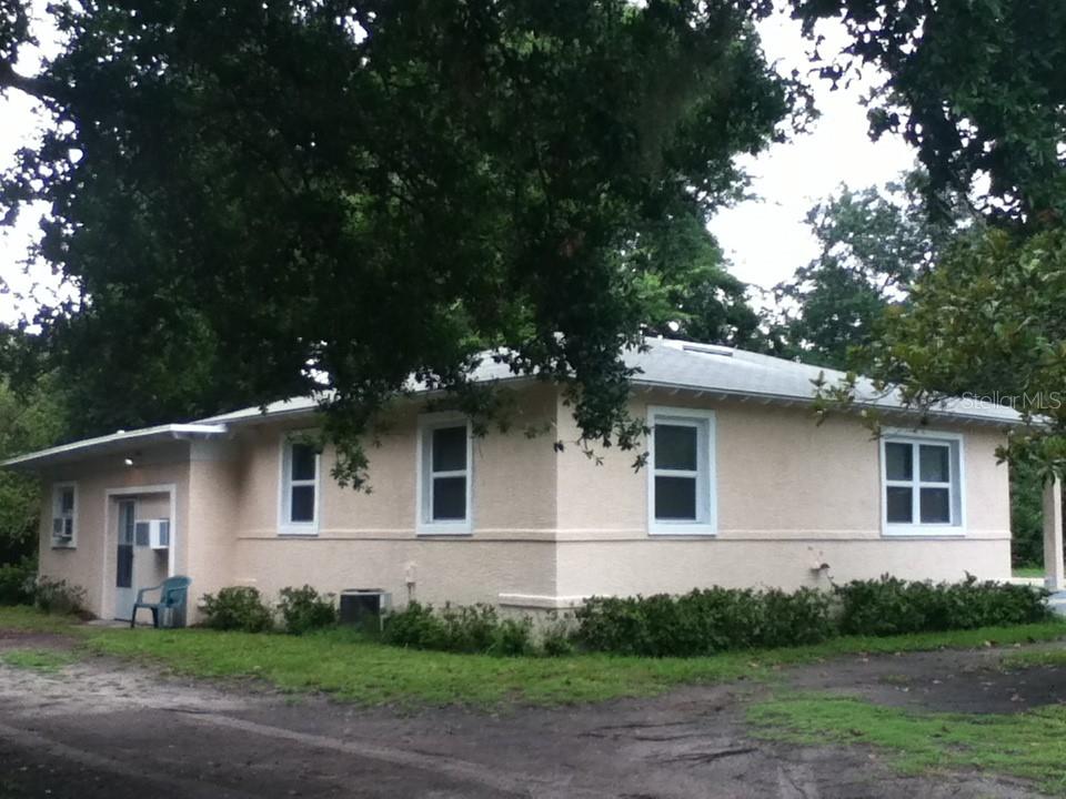 A single-story, light-colored stucco house with a hip roof sits on a grassy lot — 486 OAK STREET, NEW SMYRNA BEACH, FL