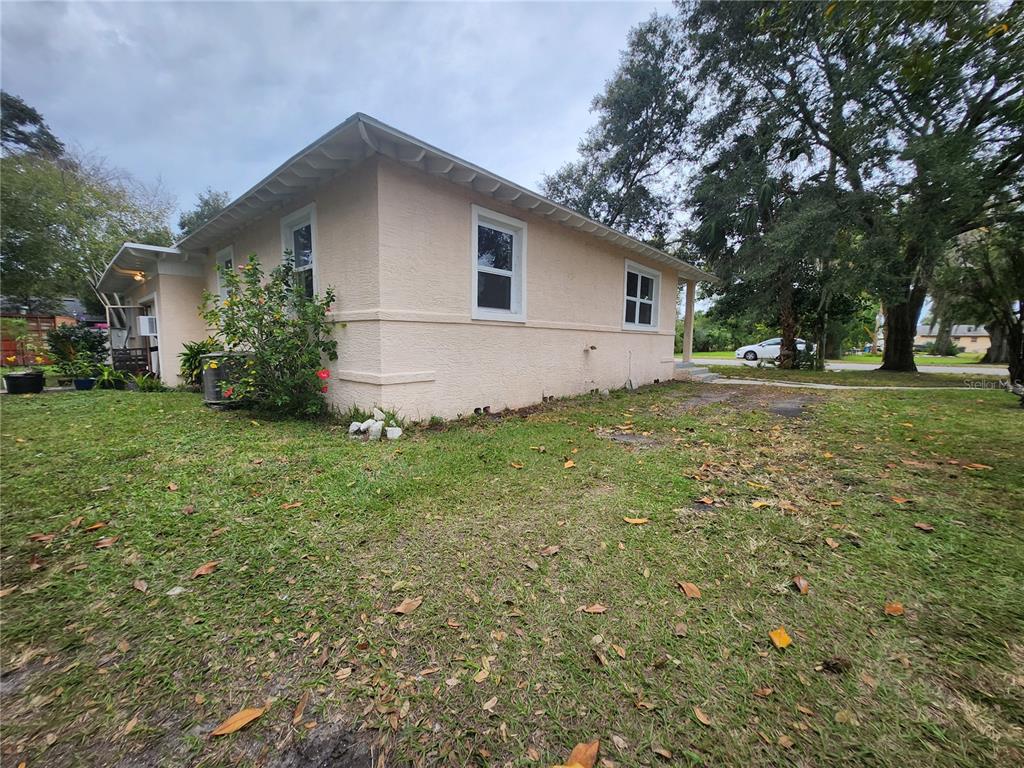 A side view of a single-story house with light-colored stucco walls and a grassy yard — 486 OAK STREET, NEW SMYRNA BEACH, FL