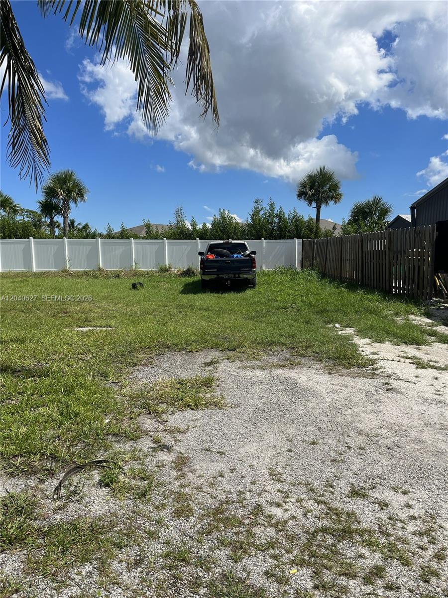 A dark pickup truck is parked on a grassy lot enclosed by a white fence — 5754 SE Green Ln, Stuart FL 34997, STUART, FL