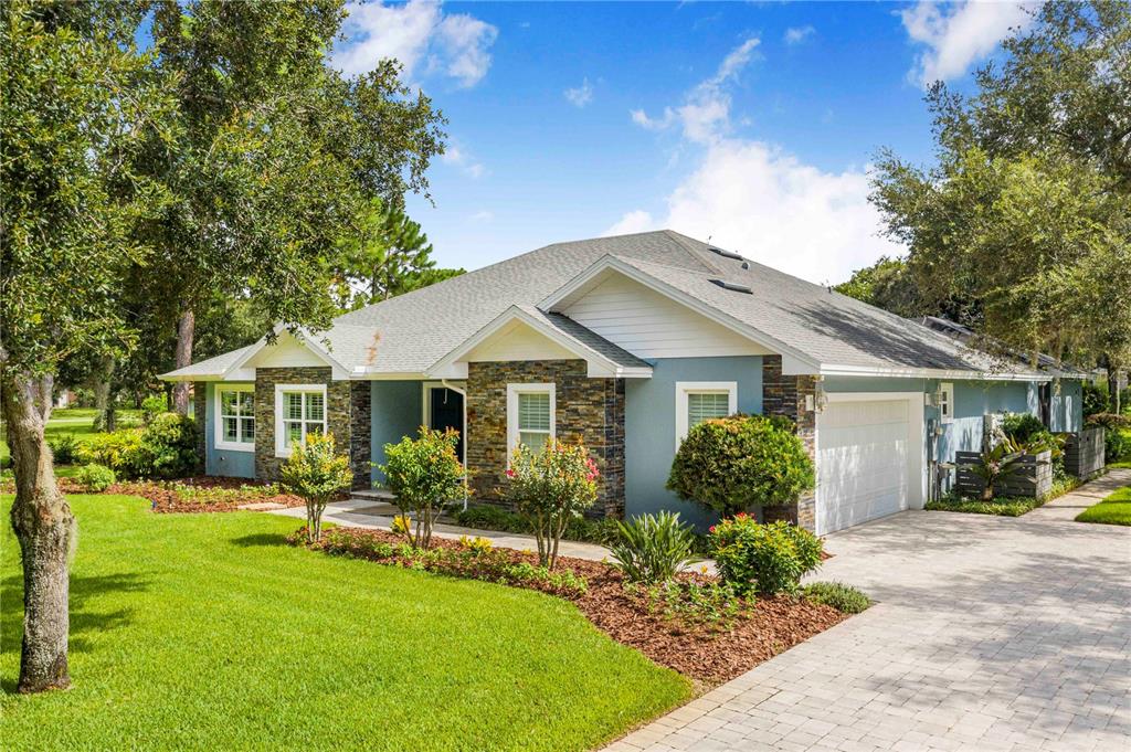 A single-story house with blue siding, stone accents, a paved driveway, and a green lawn — 2931 CHICKASAW CIRCLE, HAINES CITY, FL