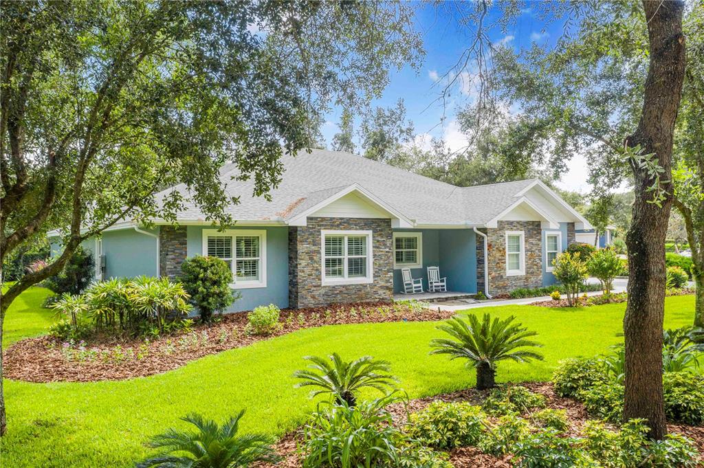 A single-story house with blue siding, stone accents, and a covered porch sits on grass — 2931 CHICKASAW CIRCLE, HAINES CITY, FL