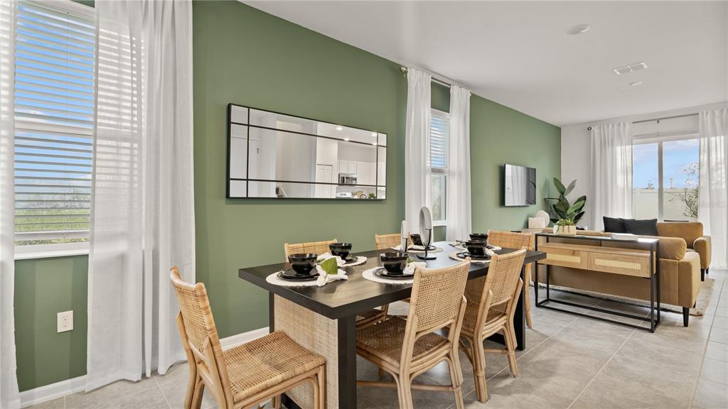 A dining area with a black table and rattan chairs sits before a green wall — 5795 ENERGY WAY, CLERMONT, FL
