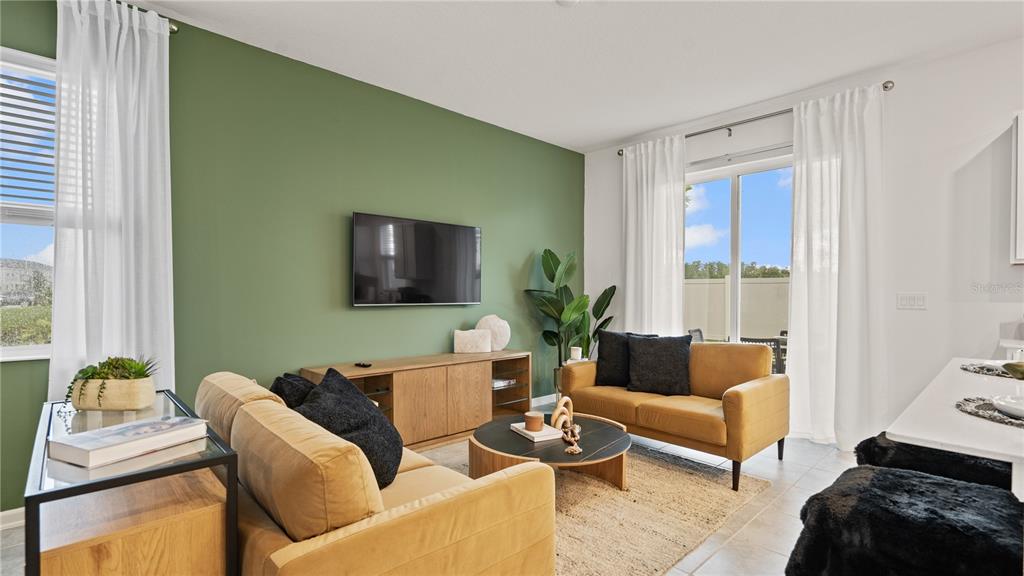A living room features a green accent wall, two yellow sofas, and a coffee table — 5795 ENERGY WAY, CLERMONT, FL
