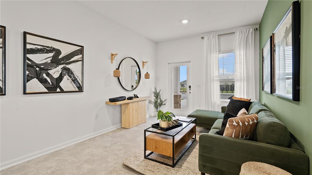 A living room features a green sectional sofa, a wooden console table, and abstract wall art — 5795 ENERGY WAY, CLERMONT, FL