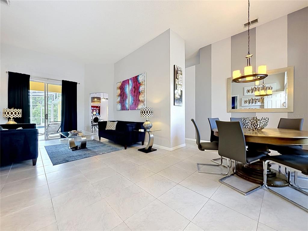 A dining area and living room feature tile floors, modern furniture, and a large mirror — 844 MONTANA AVENUE, DAVENPORT, FL