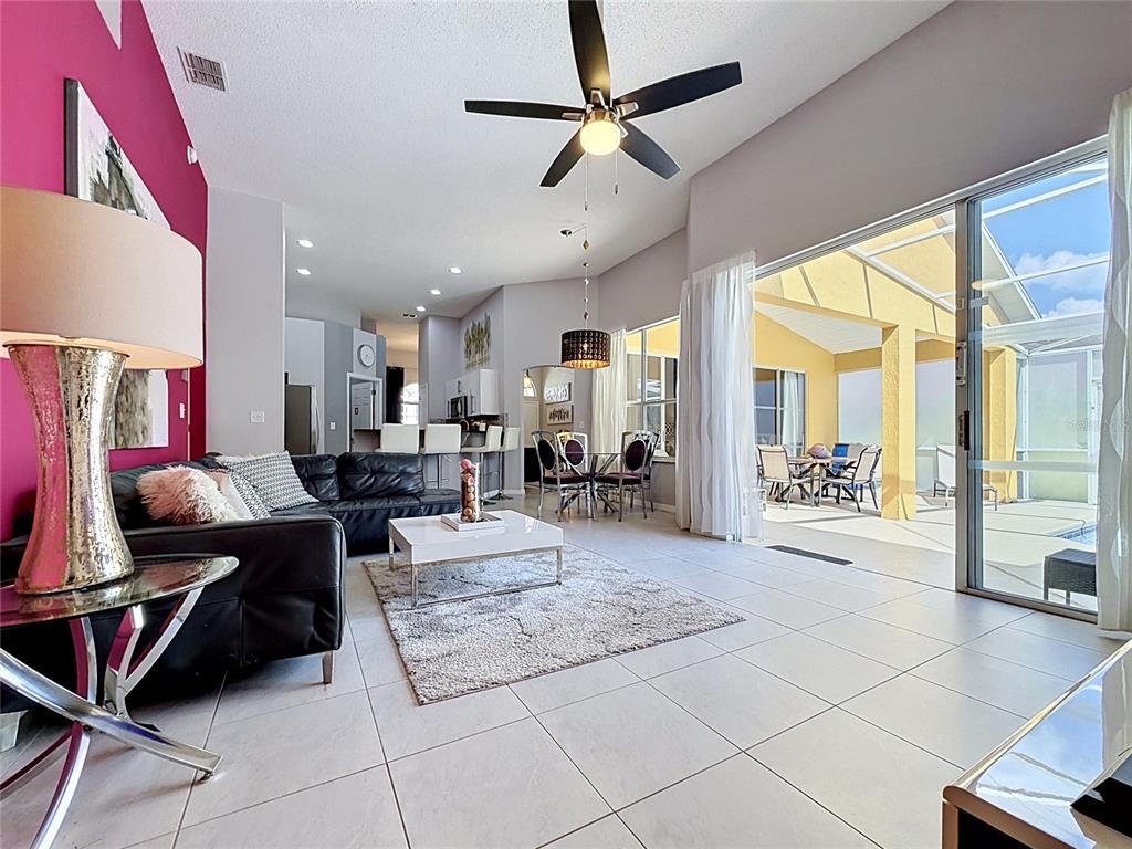 A living room with tile floors, a black sofa, and sliding doors to a patio — 844 MONTANA AVENUE, DAVENPORT, FL