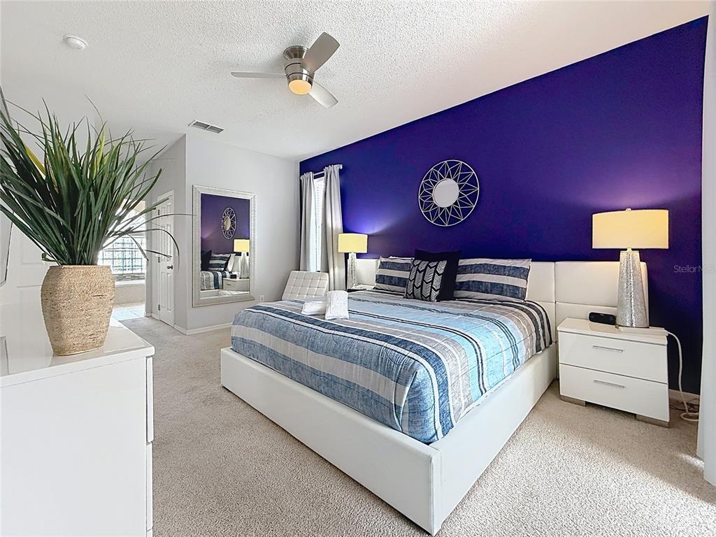 A bedroom features a purple accent wall, a white platform bed, and a ceiling fan — 844 MONTANA AVENUE, DAVENPORT, FL