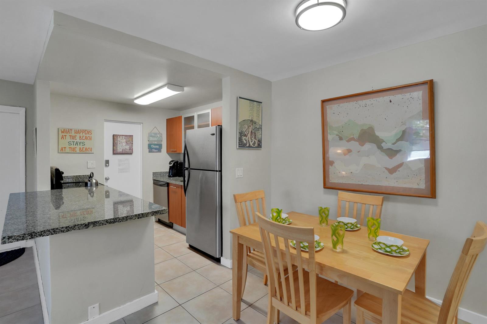 A kitchen with granite countertops and stainless steel appliances sits beside a wooden dining set — 3212 NE 9th # A104, Pompano Beach FL 33062, POMPANO BEACH, FL