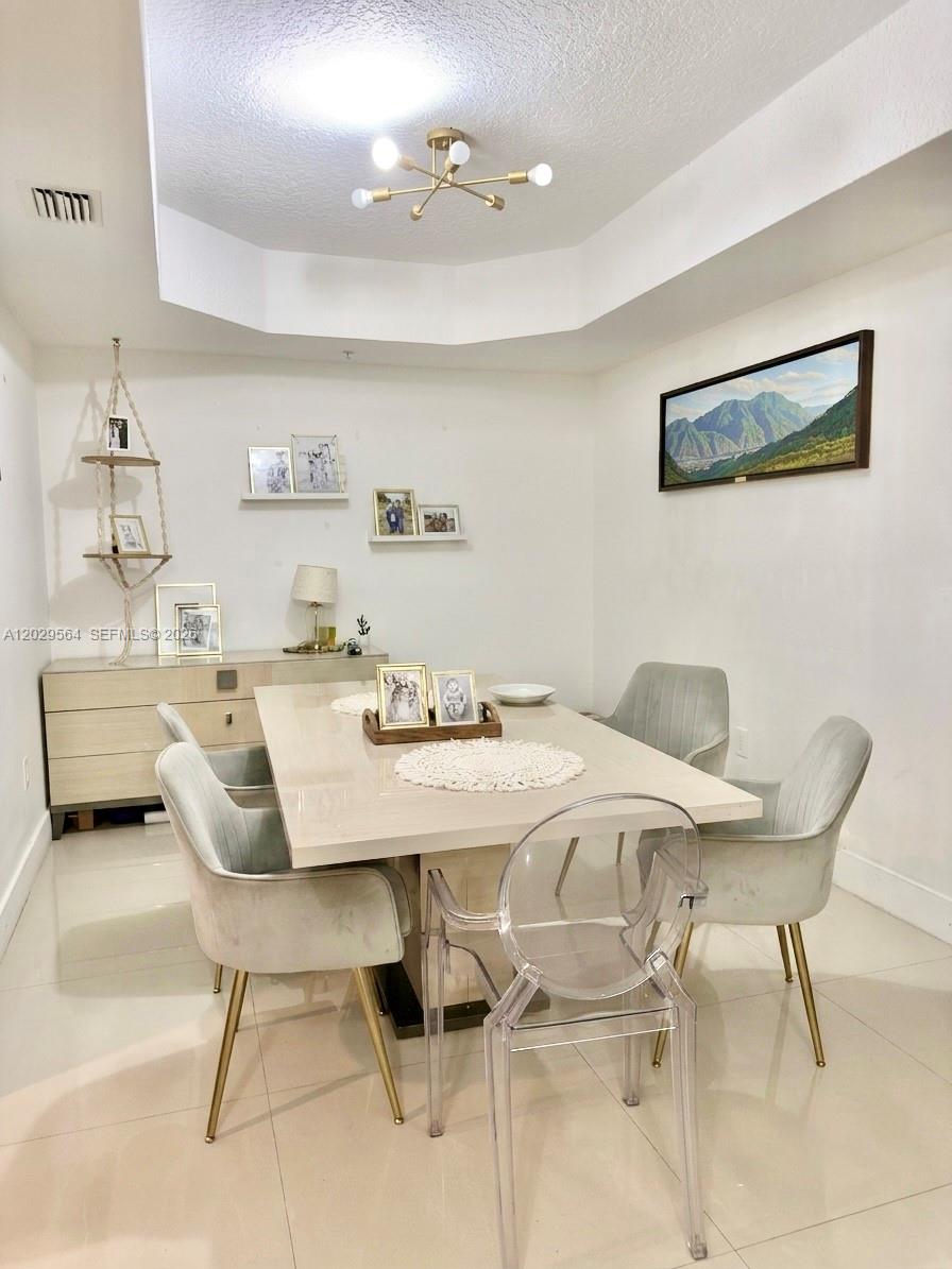 A dining room features a light-colored table, upholstered chairs, a sideboard, and a modern chandelier — 6540 NW 114th Ave # 1408, Doral FL 33178, DORAL, FL