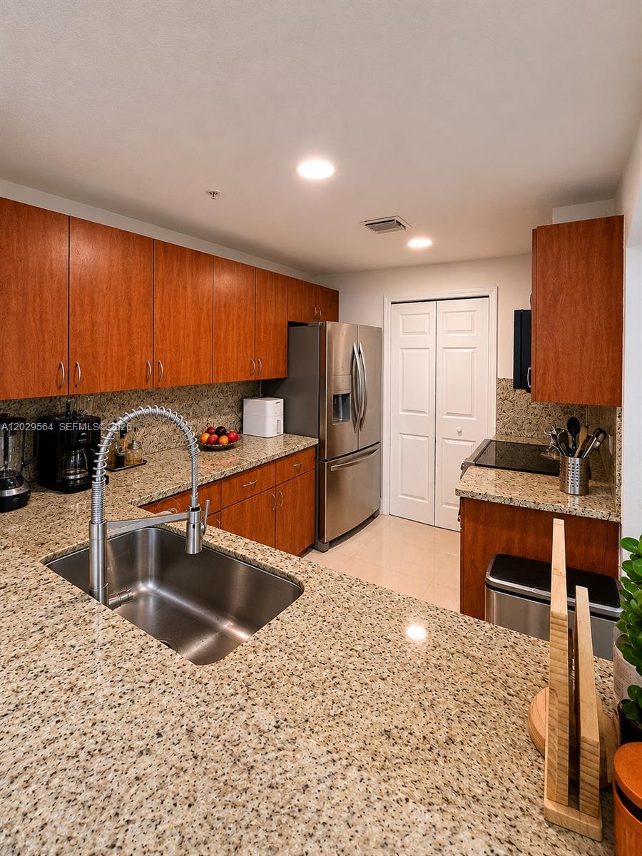 A kitchen features wood cabinets, granite countertops, stainless steel appliances, and a double-basin sink — 6540 NW 114th Ave # 1408, Doral FL 33178, DORAL, FL